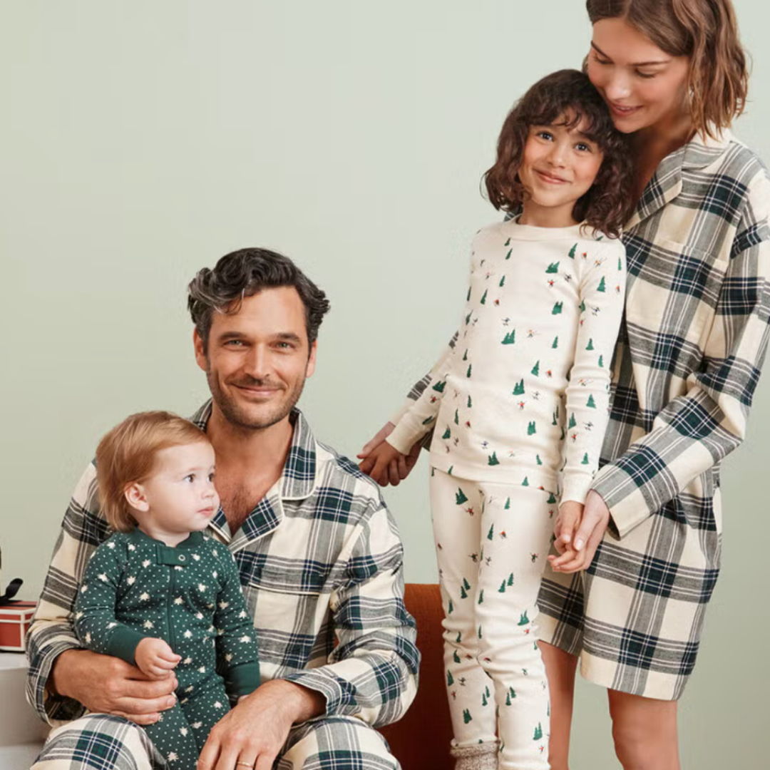 Family of four wearing matching pajamas against a light green background