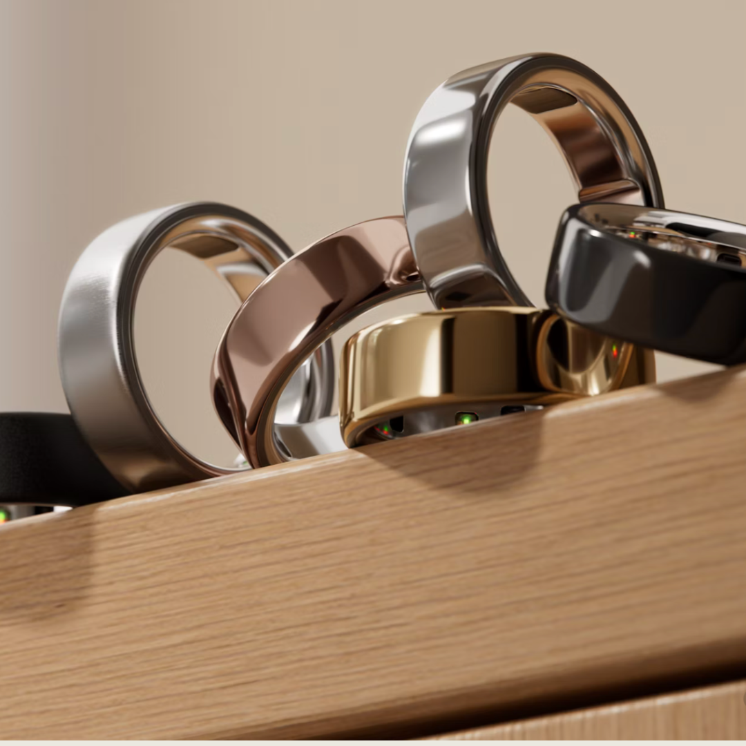 Assortment of different color Oura rings on a wooden surface with a neutral background
