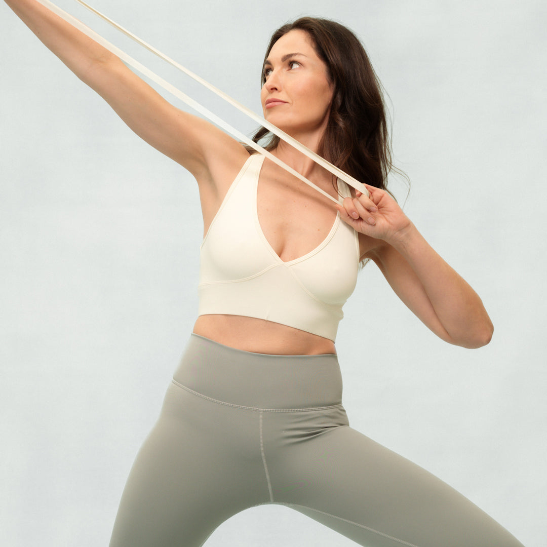 Woman exercising with resistance bands against a light gray background