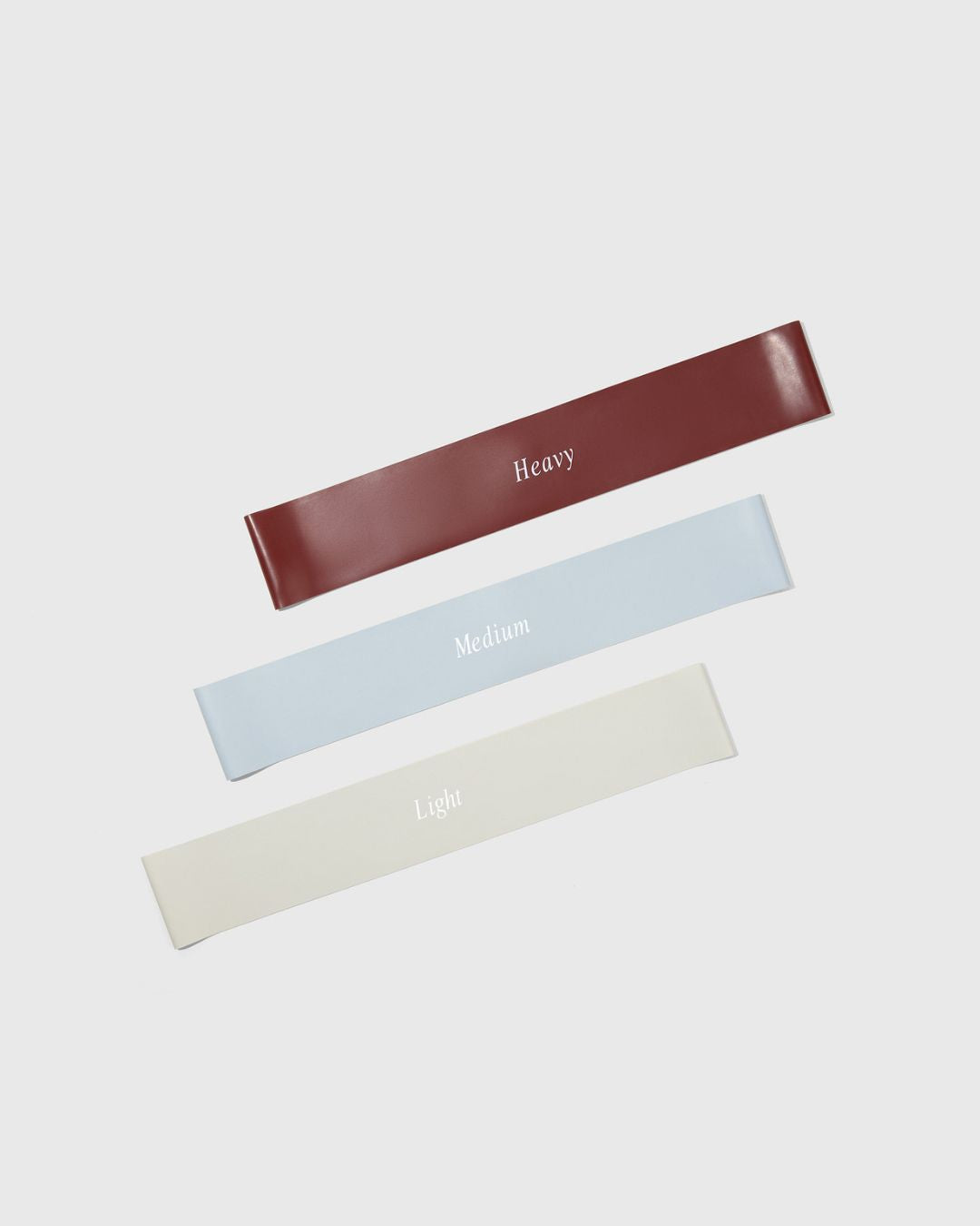 3 rubber workout bands in 3 weights heavy, medium, and light laying flat and diagonally