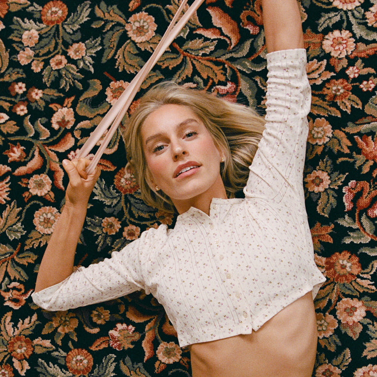 Katy lying on a floral-patterned carpet holding a workout band