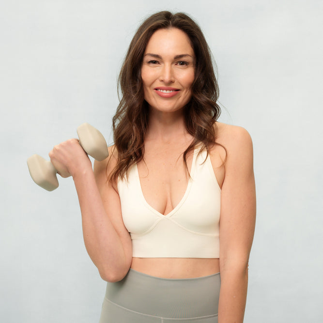 Woman holding a dumbbell against a light gray background