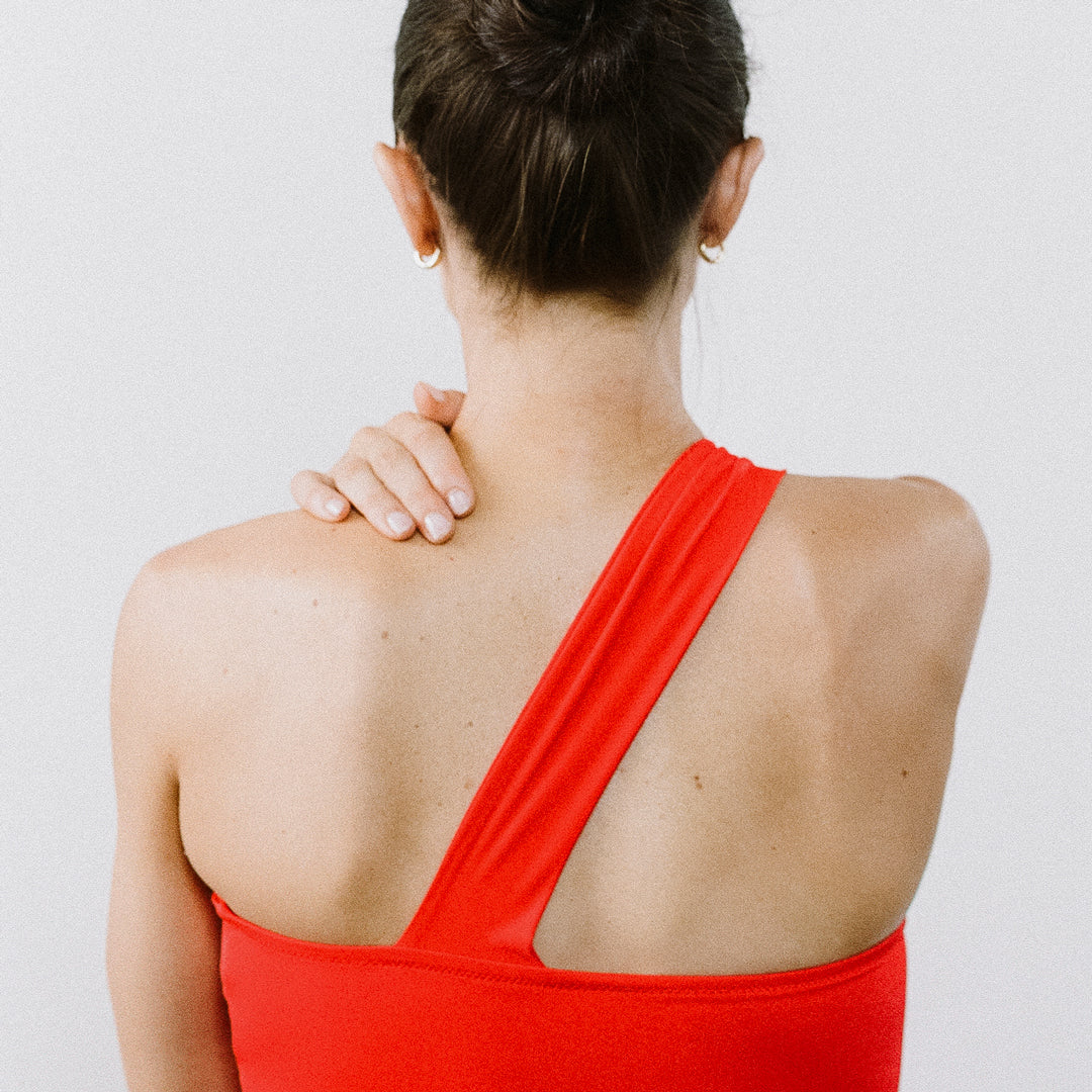 Woman wearing a red dress with a cutout design on a plain background